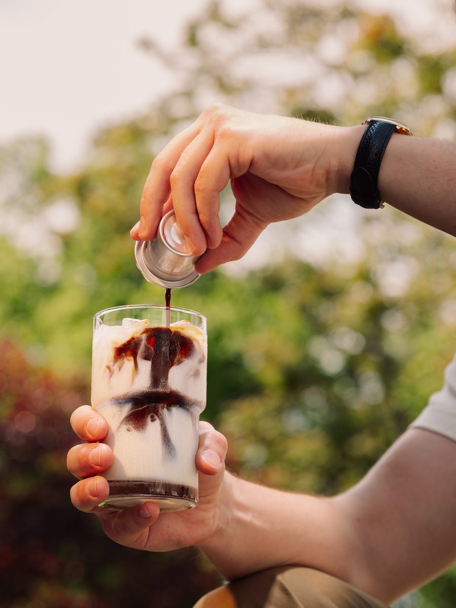 Pouring Cometeer coffee from a capsule into iced milk