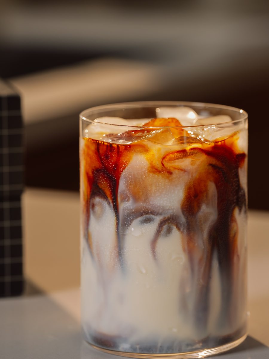 Iced coffee with cream swirling through the glass