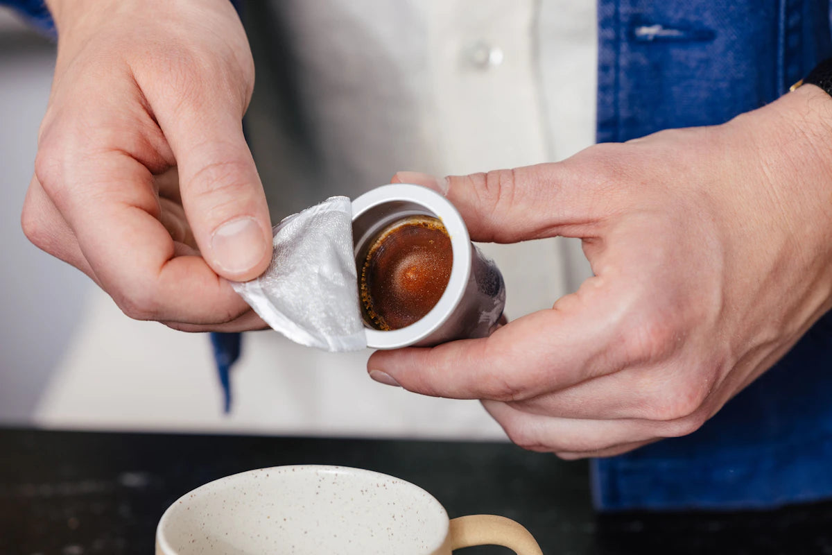 Hands opening a Cometeer capsule above a cup