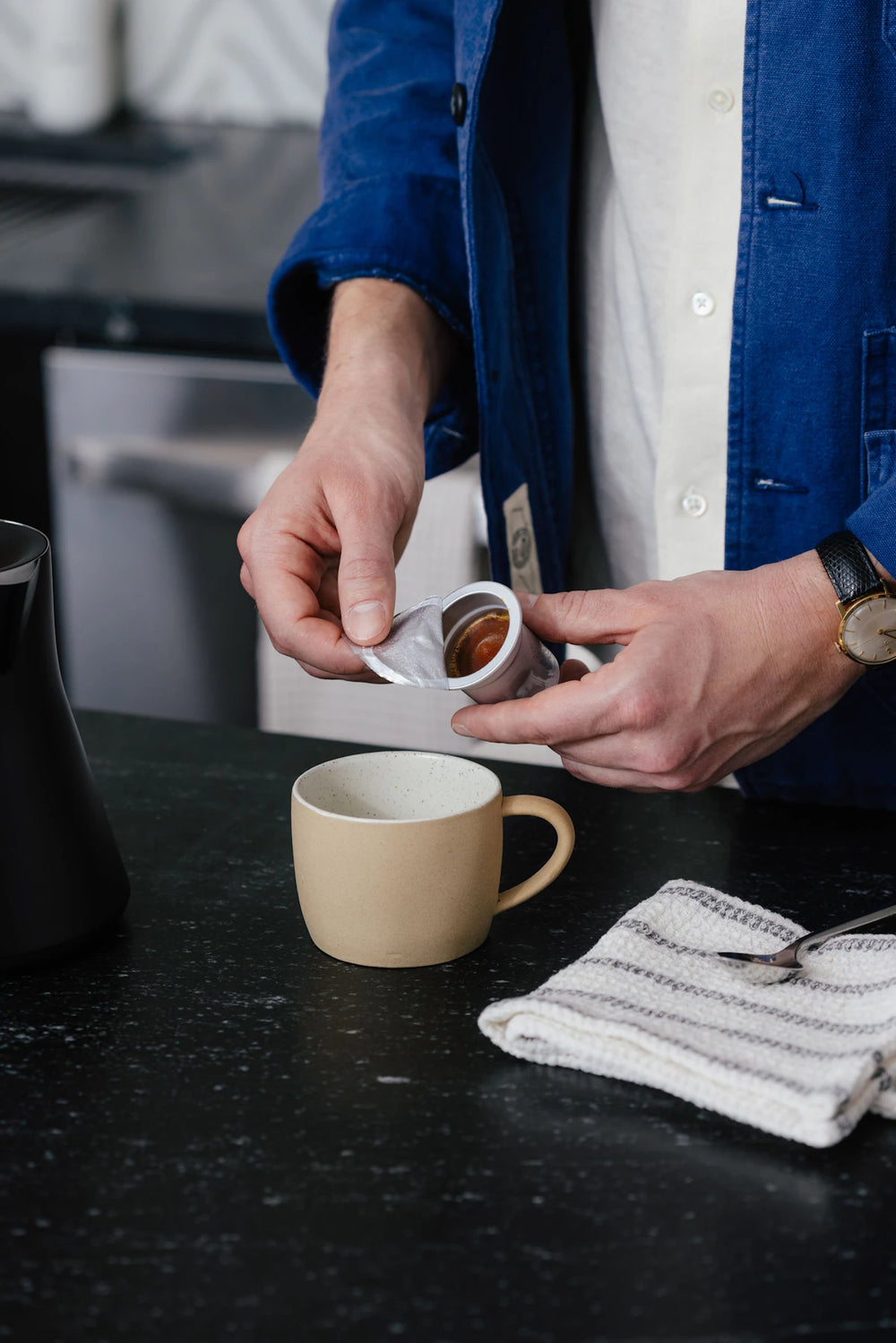 Opening a Cometeer frozen coffee capsule above a ceramic mug.
