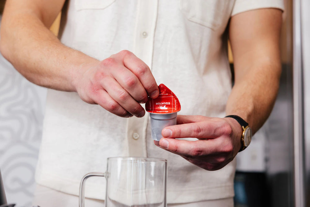 Peeling the lid from an Equator Cometeer coffee capsule.