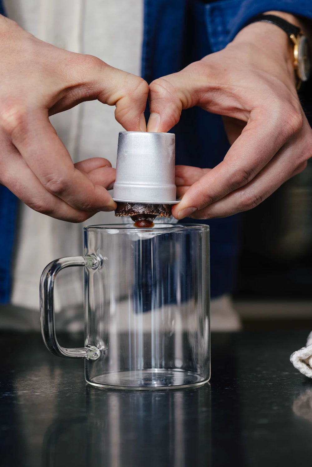 Releasing frozen Cometeer coffee from its capsule into a glass mug.